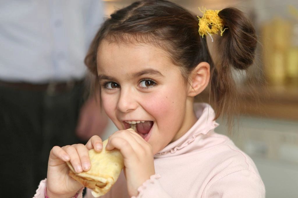Happy girl taking a big bite of a crepe